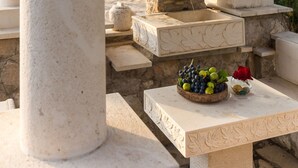 A stone fireplace with a fruit bowl and a vase with a red flower on a table.