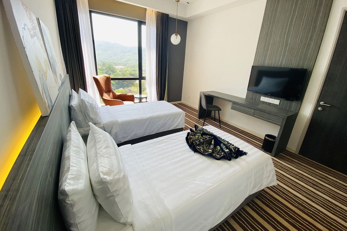 A hotel room with two beds, a TV, a desk, and a view of the outdoors.