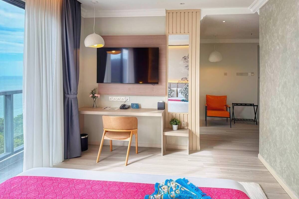 Une chambre d’hôtel moderne dotée d’un grand lit, d’un bureau avec une chaise, d’une télévision et offrant une vue sur l’extérieur.