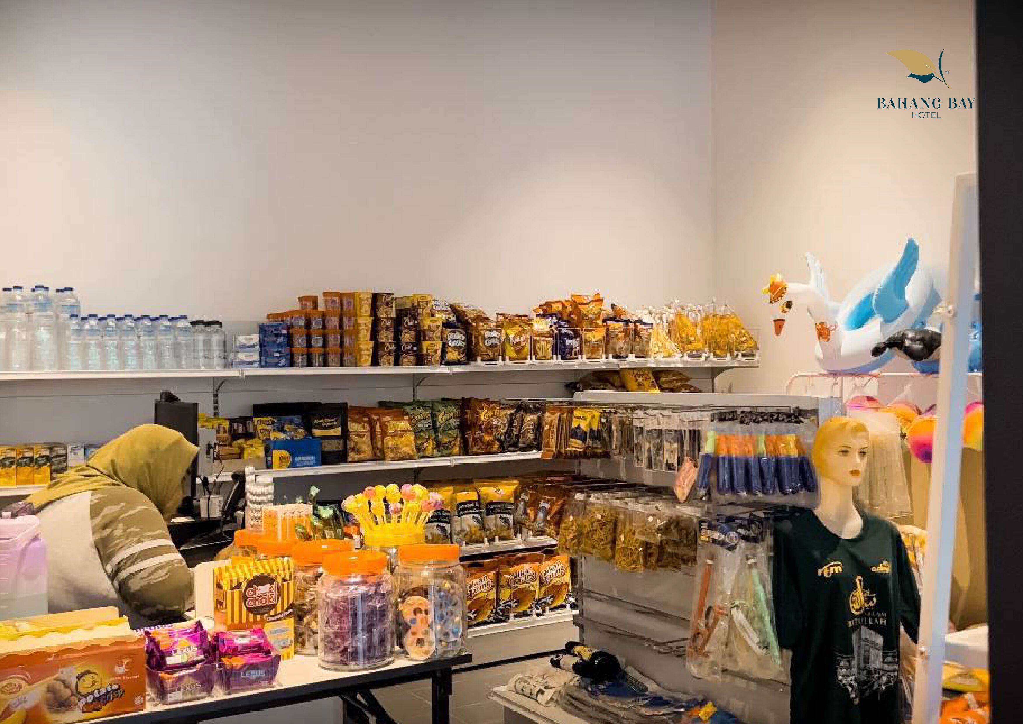 A retail section of a hotel with shelves stocked with snacks, bottled water, and other items.