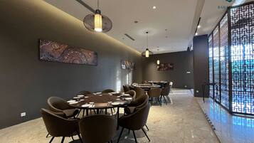 Un comedor moderno con mesas y sillas redondas, iluminación colgante y decoración en la pared.