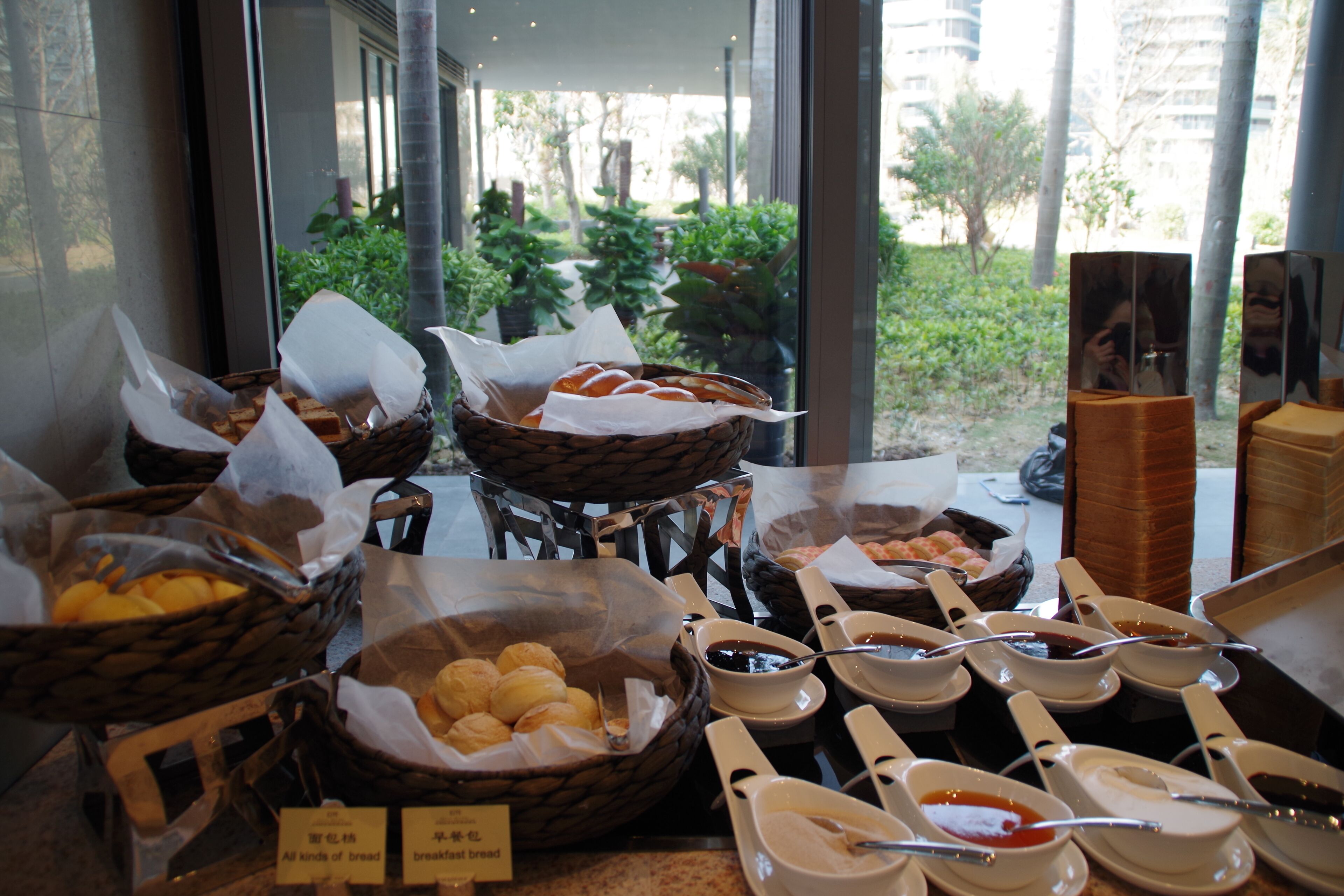 Un buffet de petit-déjeuner proposant une variété de pains et de viennoiseries, accompagné de plusieurs condiments et sauces.