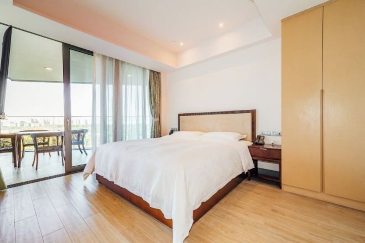Een moderne hotelkamer met een groot bed, een houten vloer, een bureau en een kledingkast.