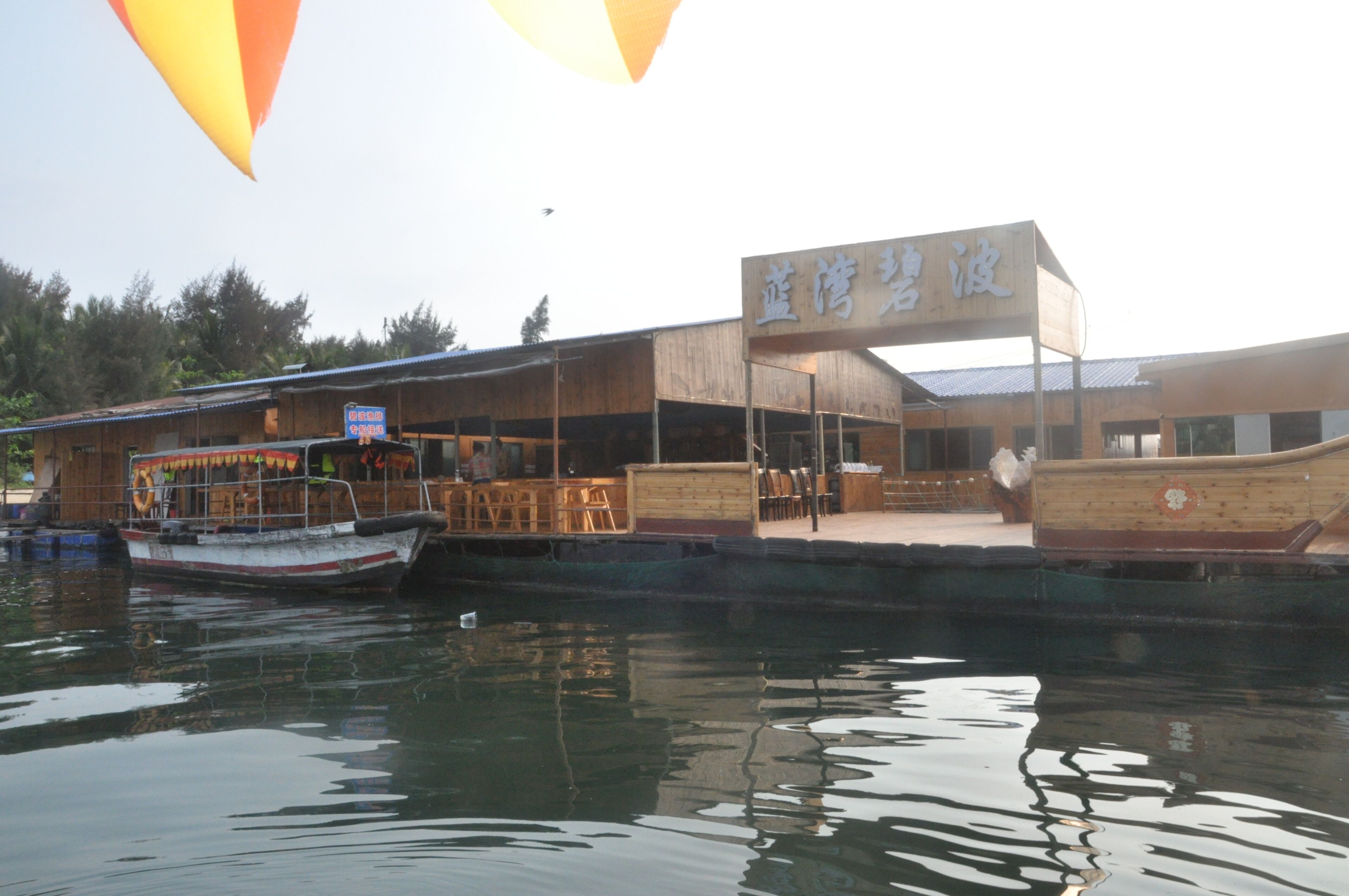 A waterfront restaurant with a wooden exterior and a sign in a foreign script.