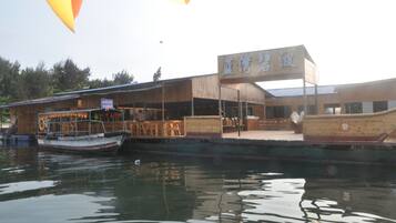 A waterfront restaurant with a wooden exterior and a sign in a foreign script.