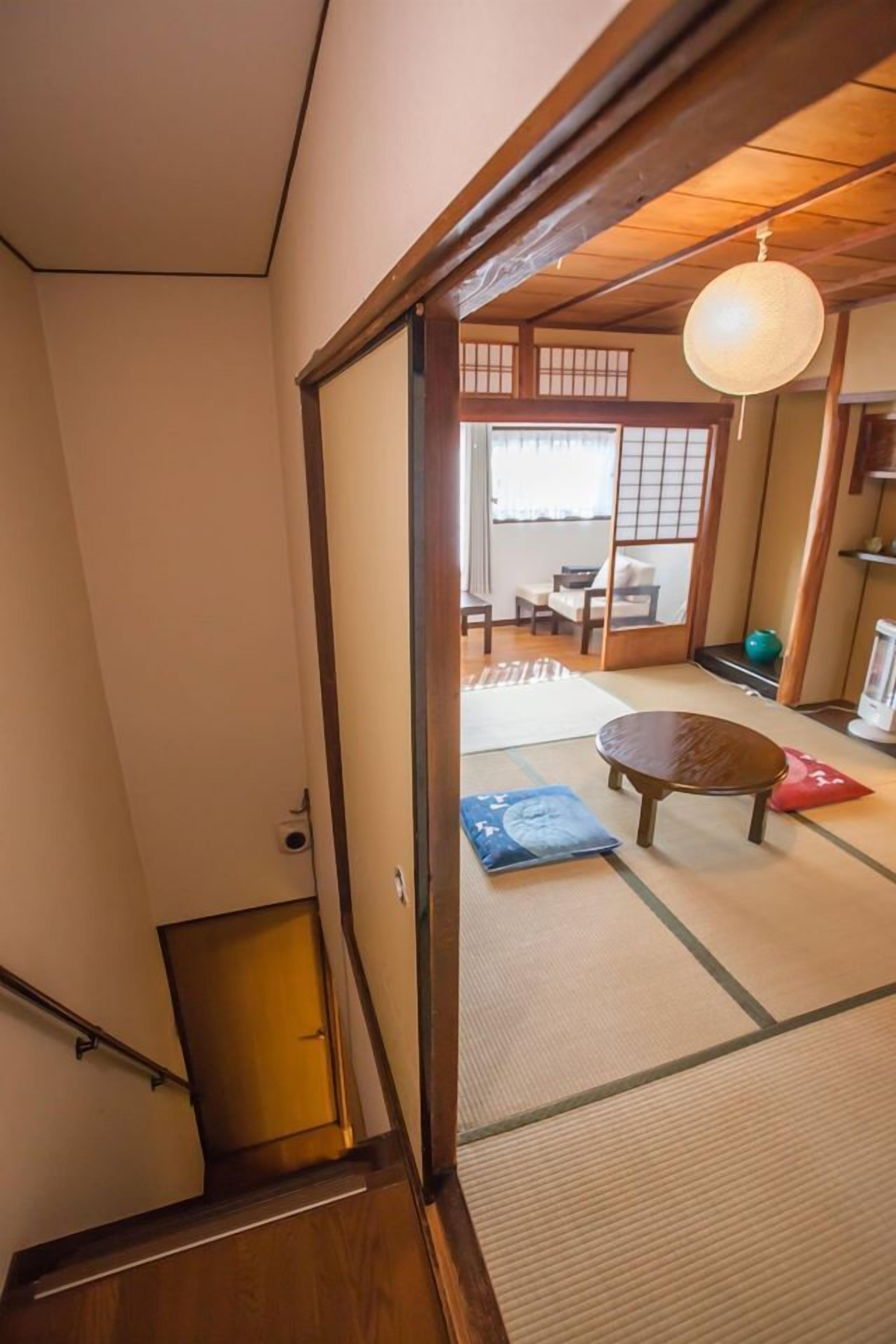 Een traditionele Japanse kamer met tatami vloeren, een lage houten tafel en een schuifdeur naar een balkon.