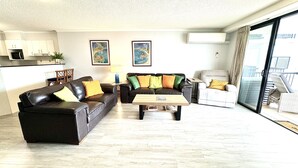 Ein großzügiger Wohnbereich mit zwei Sofas, einem Couchtisch und einem Balkon mit Korbmöbeln.