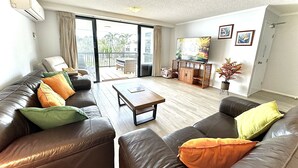 Ein Wohnzimmer mit Ledersofas, einem Holztisch und einem Fernseher auf einem Holzboden.