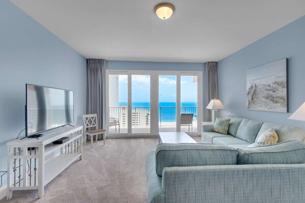 A modern hotel room with a balcony, a television, a sofa, and a painting.