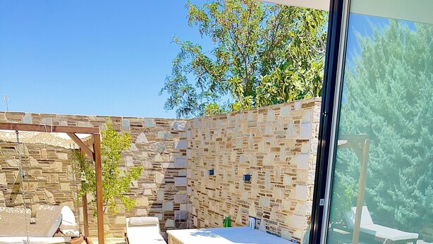 Bandeja de desayuno con alimentos y bebidas, una rosa y toallas sobre una cama con vistas a una piscina y zona de estar al aire libre.