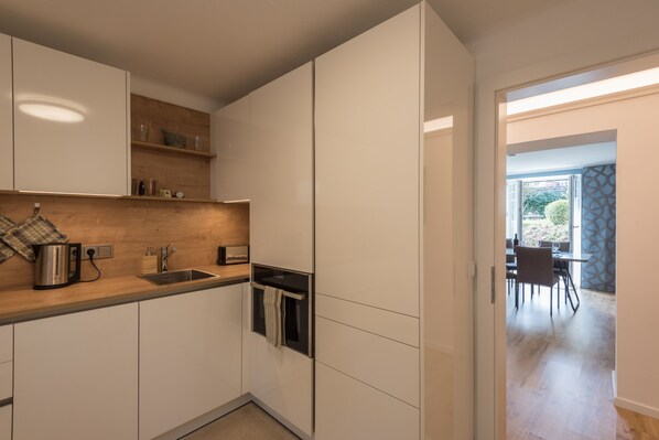 Una cocina moderna con armarios blancos, encimera de madera y horno empotrado.