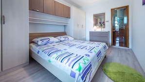 A bedroom with a bed, a dresser, a mirror, and a door leading to a bathroom. - Guest House Kuna (Dubrovnik)