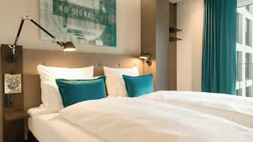 Een hotelkamer met een bed, twee wandlampen, een ingelijst schilderij en een raam met gordijnen.