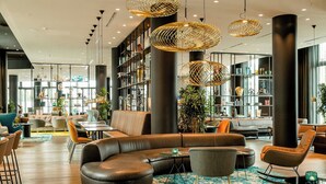 A modern lounge area with leather sofas, a coffee table, and a bookshelf filled with decorative items.