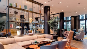 A modern lounge area with a beige sofa, blue armchairs, and a glass display case filled with decorative items.
