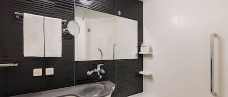 Un baño moderno con pared de azulejos blanco y negro, un lavamanos blanco, un espejo y una zona de ducha.