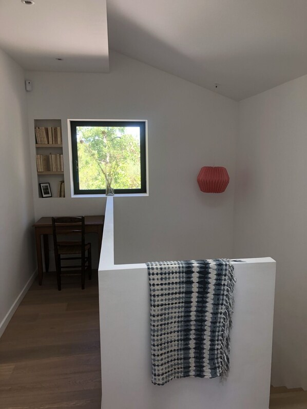 A modern room with a desk, chair, and a window with a view of greenery.