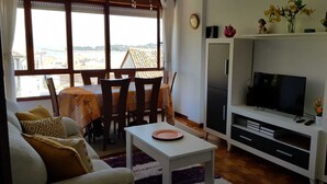 Ein Wohnzimmer mit Fernseher, Esstisch und Stühlen.