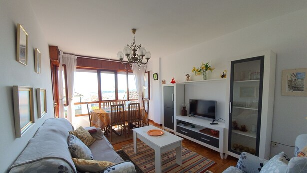 Ein Wohnzimmer mit Sofa, TV-Schrank, Esstisch und Stühlen.