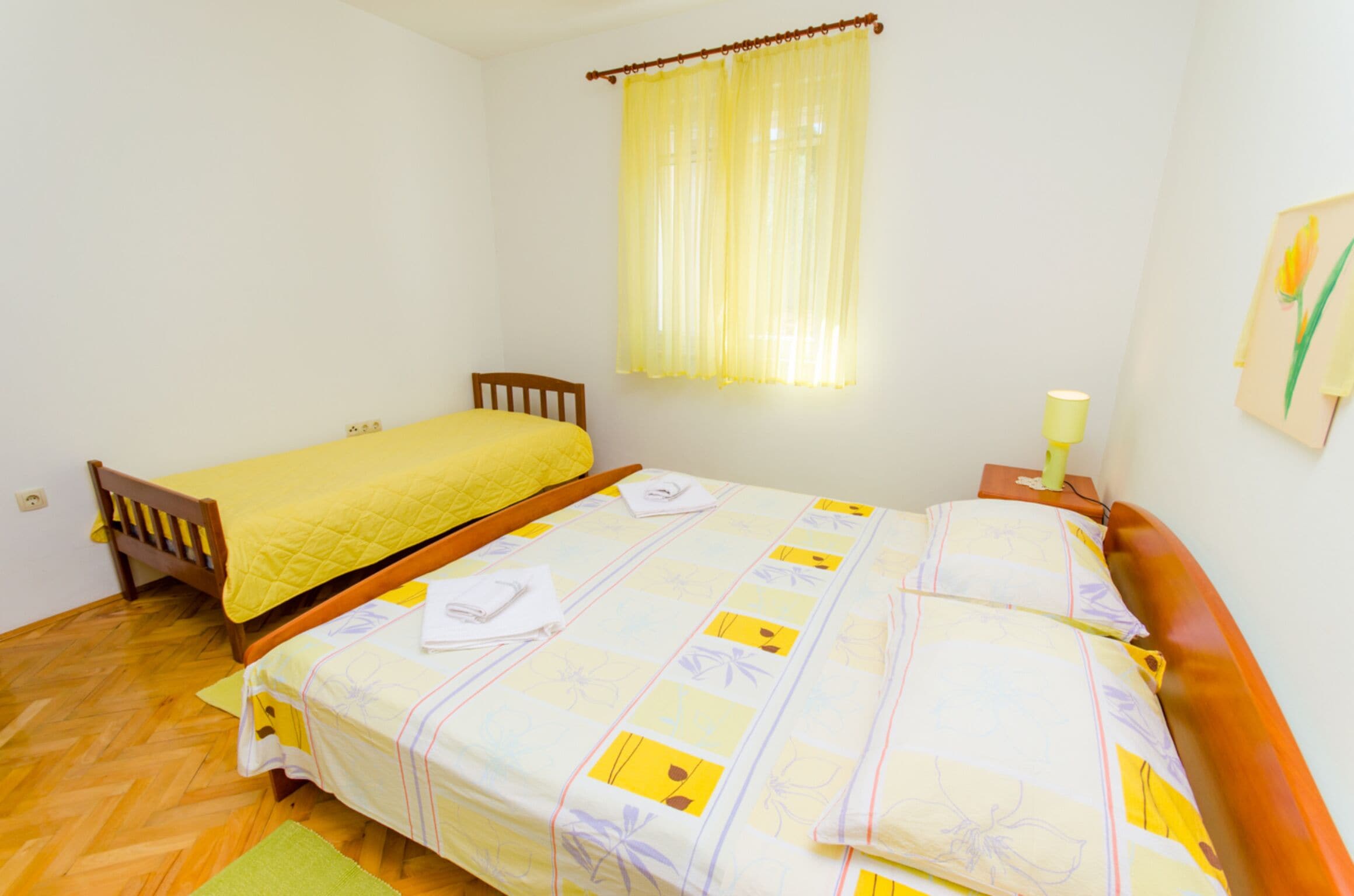 A double bed with a yellow bedspread and a single bed with a yellow blanket.