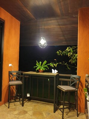 Relax in this serene outdoor seating area with a hanging light, two chairs, and a small table.