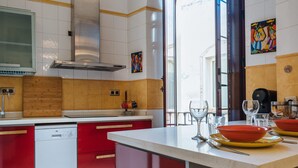 Una cucina moderna con mobili rossi e bianchi, lavastoviglie integrata e una grande isola con sgabelli da bar.