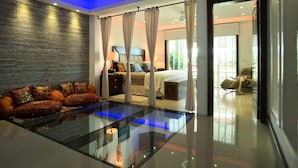 A modern hotel room with a glass coffee table, a bed with a canopy, and a stone-textured wall. - Luxury Duplex  2 MIN to 5th , Beach & Tourist Aera (Playa del Carmen)
