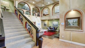 A spacious interior with a grand staircase, a dining area, and a large painting on the wall.