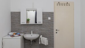 Une salle de bain avec un lavabo blanc, un miroir et un porte-serviettes.