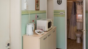 Une cuisine compacte équipée d’un four à micro-ondes, d’une bouilloire et d’un placard.
