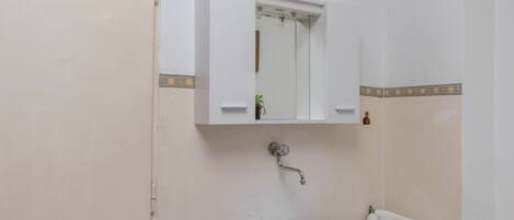 A bathroom with a white sink, a mirror, and a towel hanging on the wall.