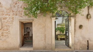 Un bâtiment en pierre avec une porte ouverte donnant sur une pièce où se trouvent une table et des chaises.