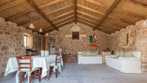 Un interno rustico in pietra con zona pranzo, un divano e una piccola finestra.