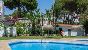 Piscina amb escales de pedra i baranes metàl·liques, envoltada de vegetació exuberant i palmeres.