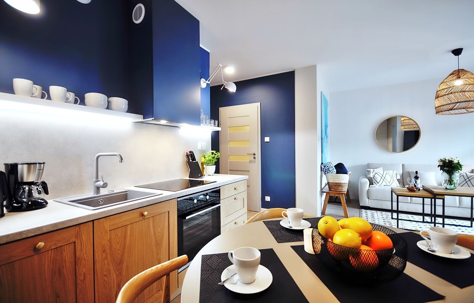 A modern kitchen with a built-in dishwasher, a coffee machine, and a dining area with a table set for two.