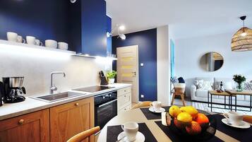 A modern kitchen with a built-in dishwasher, a coffee machine, and a dining area with a table set for two.