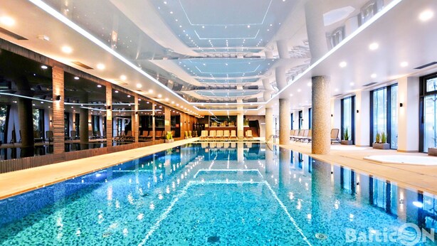 A modern indoor swimming pool with clear blue water, surrounded by lounge areas and large windows. - BalticON Nadmorskie Tarasy (Kolobrzeg)