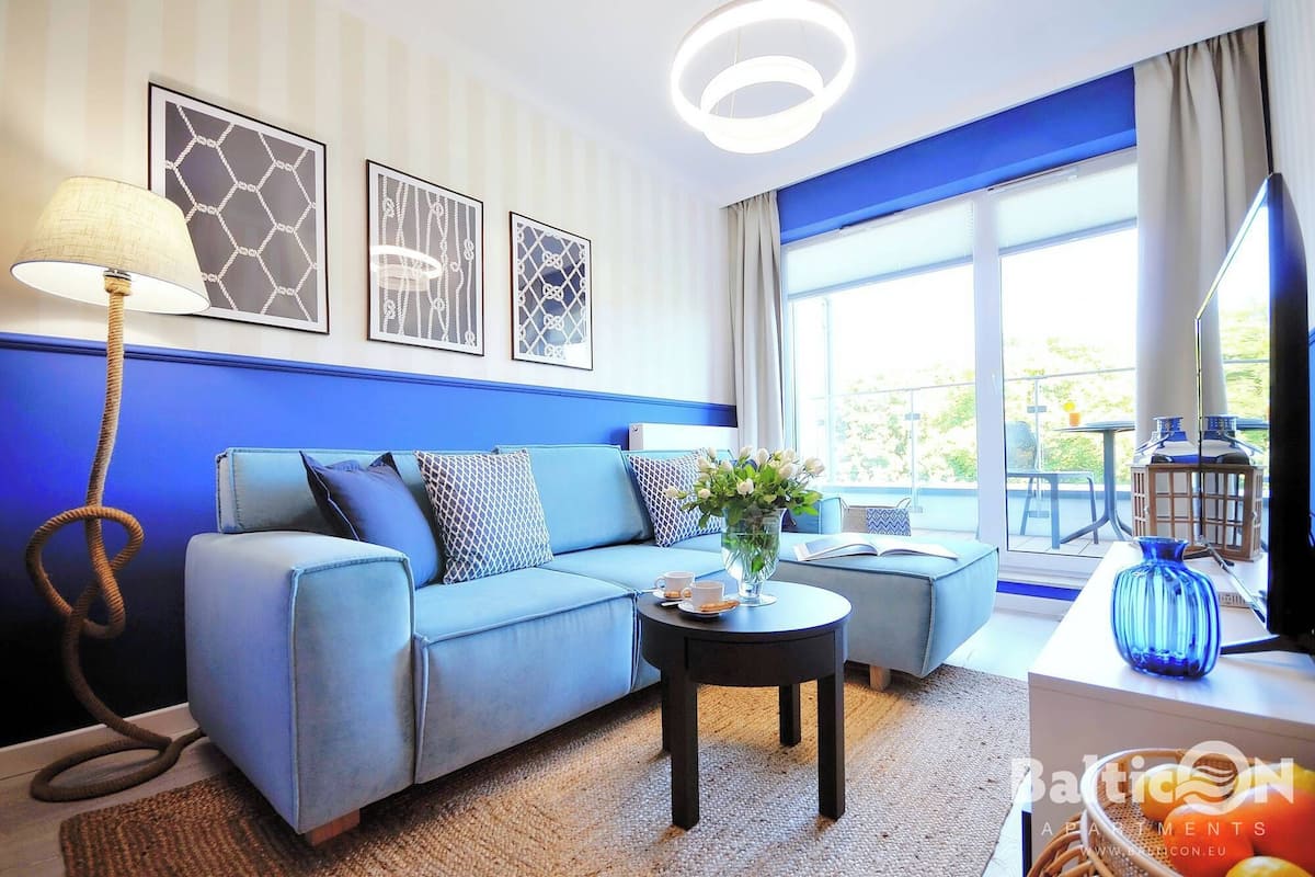 Ein modernes Wohnzimmer mit einem blauen Sofa, einem Couchtisch und Blick ins Freie.