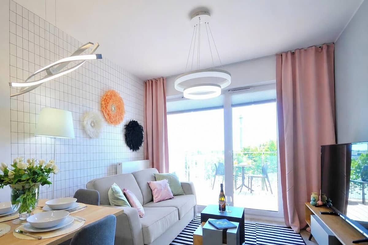 Ein modernes Wohnzimmer mit Essbereich, einer Couch, einem Flachbildfernseher und einem großen Fenster mit Vorhängen.