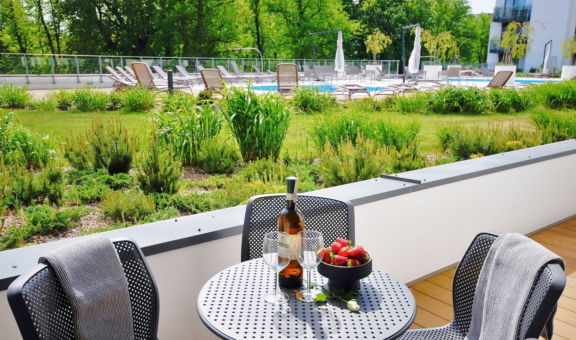 A rooftop terrace with a pool, lounge chairs, and a table with a bottle and strawberries.