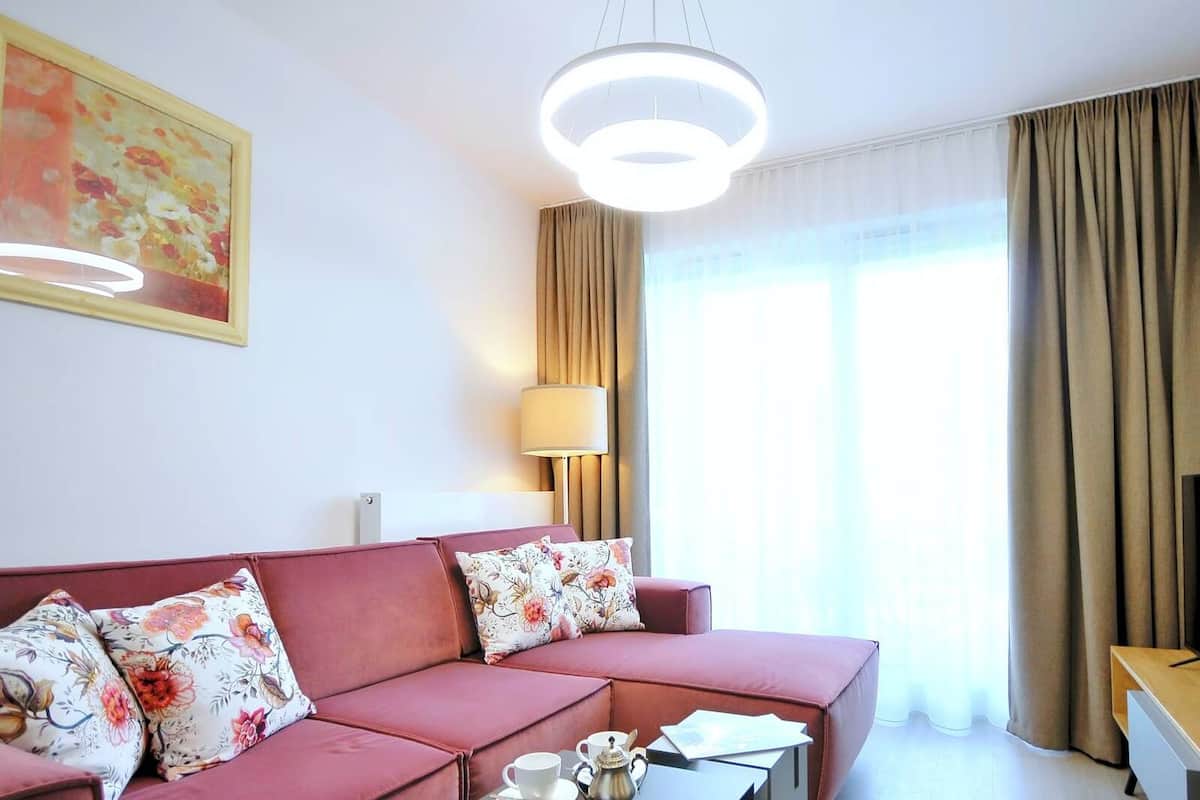 Ein modernes Hotelzimmer mit einem roten Sofa, einem Flachbildfernseher, einer Lampe und einem Bild an der Wand.