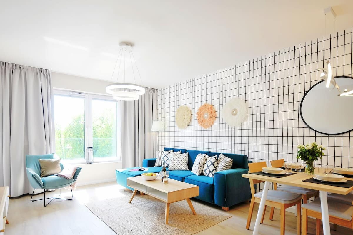 Ein modernes Wohnzimmer mit einem blauen Sofa, einem Esstisch und einer Küchenzeile.