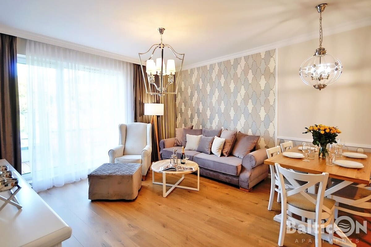 Ein modernes Wohnzimmer mit Sofa, Sessel, Couchtisch und Esstisch, gedeckt für eine Mahlzeit.