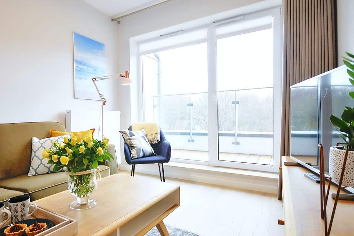 Ein modernes Wohnzimmer mit Sofa, Couchtisch und großem Fenster mit Blick ins Freie.