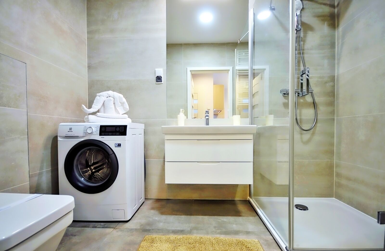 A modern bathroom with a washing machine, a sink, and a shower.
