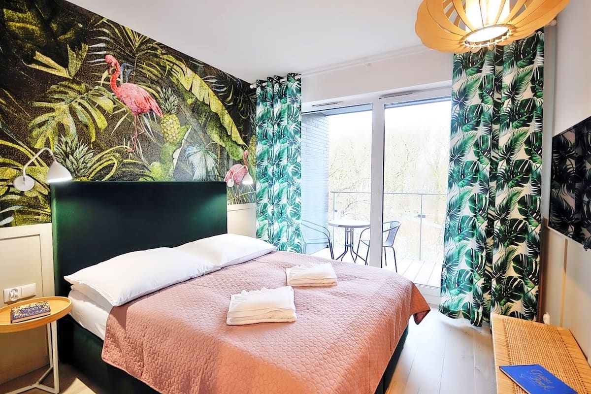 Ein Hotelzimmer mit Bett, Nachttisch, kleinem Tisch und Balkon mit Aussicht.