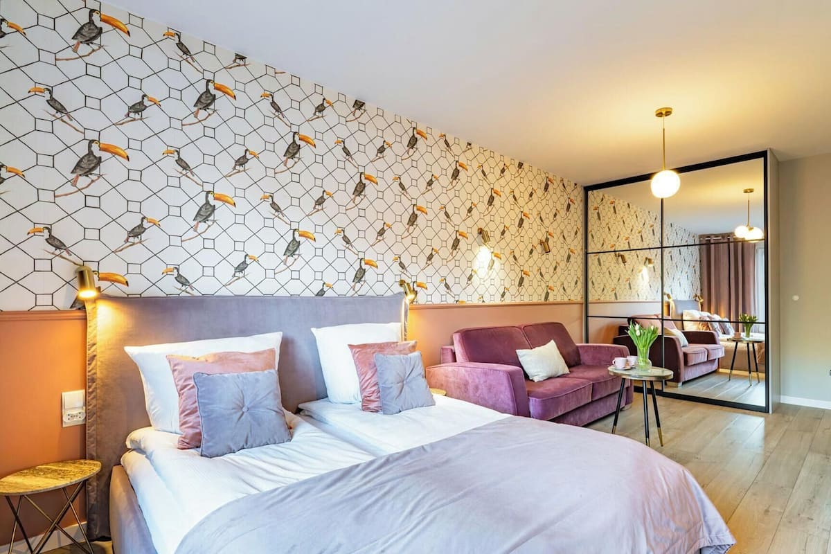 Ein modernes Hotelzimmer mit einem großen Bett, einer Couch, einem kleinen Tisch und einem Spiegel.
