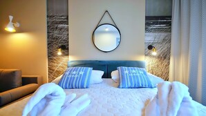 A hotel room with a bed, two pillows, a headboard, a wall-mounted mirror, and a wall with a textured pattern. - BalticON Nadmorskie Tarasy (Kolobrzeg)