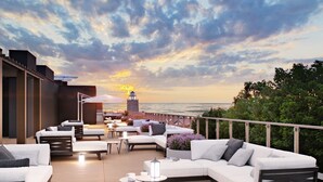 A rooftop terrace with outdoor seating and a view of the sunset over the ocean. - BalticON Nadmorskie Tarasy (Kolobrzeg)
