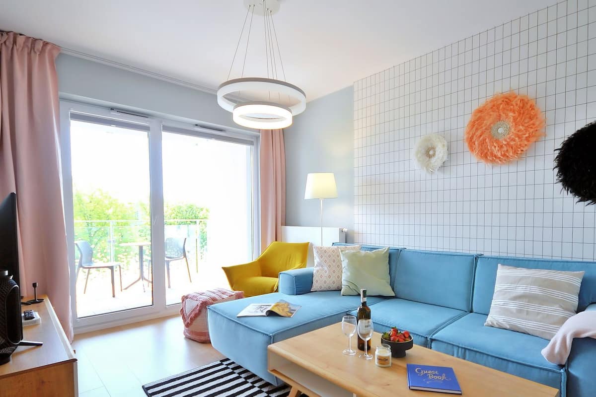 Ein modernes Wohnzimmer mit einem blauen Sofa, einem Couchtisch und einem Balkon mit Aussicht.